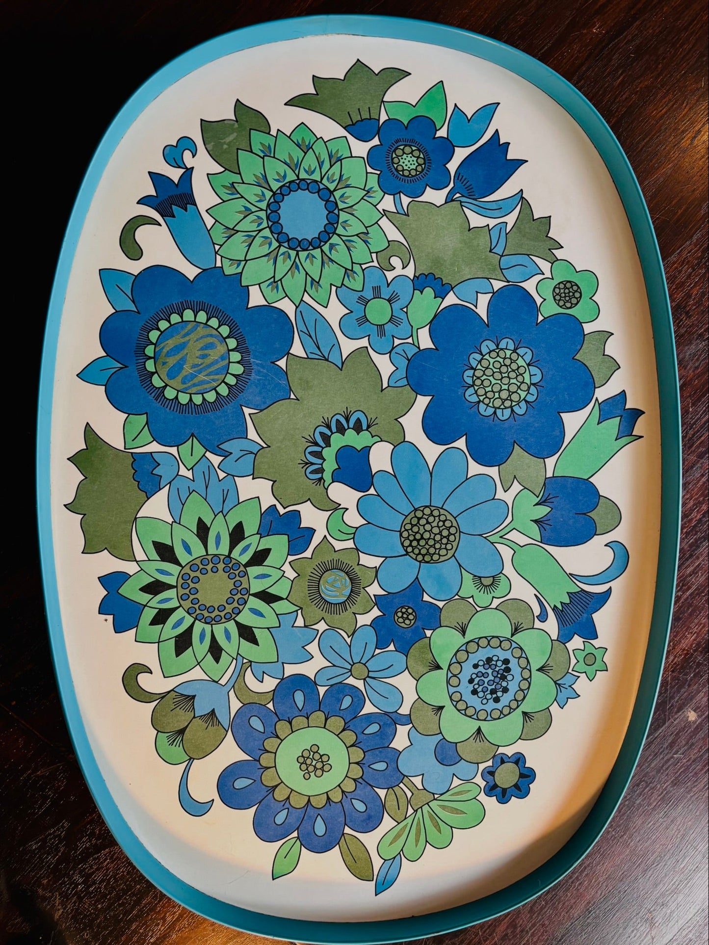 Decorative tray with blue and green floral pattern on a wooden surface