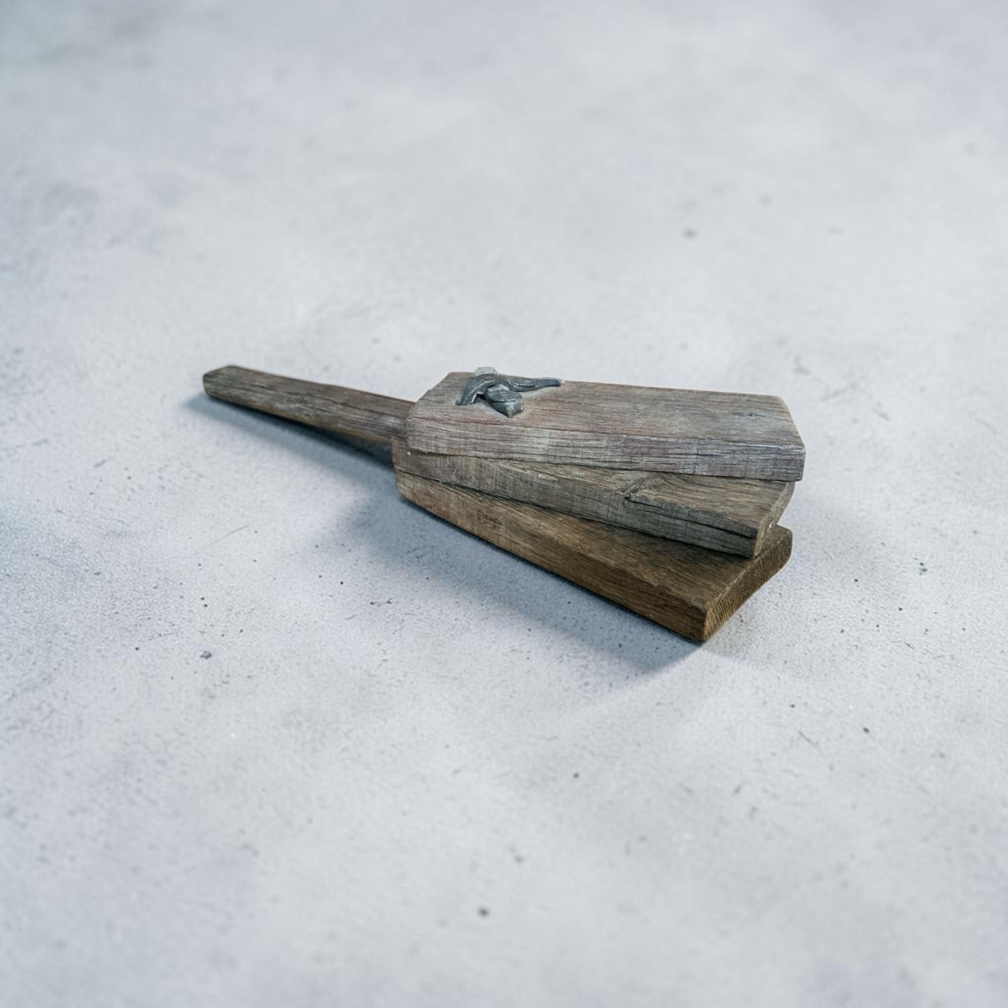 Otoch handcrafted wooden clapper made from weathered reclaimed timber with rustic metal detailing on a grey surface.
