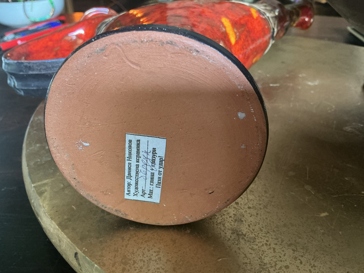 Otoch handcrafted ceramic pitcher base showing the artist signature and clay texture on a circular terracotta bottom