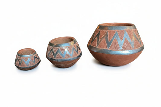 Otoch set of three handcrafted terracotta nesting bowls with metallic silver geometric zigzag patterns on a table.