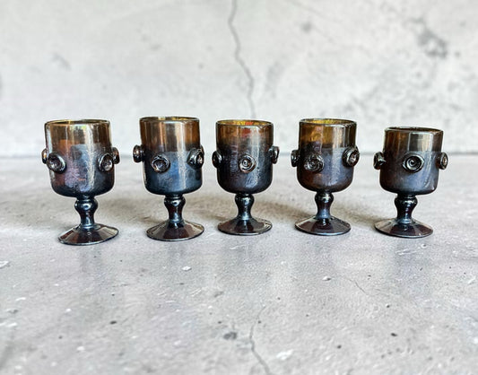 Otoch set of five vintage smoky amber glass goblets with textured circular detailing and sturdy stems.